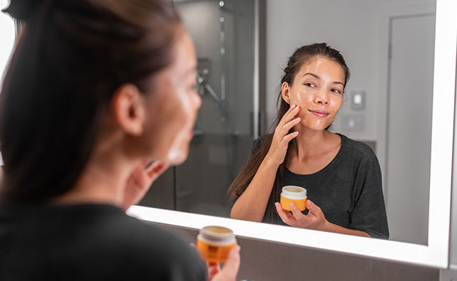 Woman Applying Moisturizer On Face